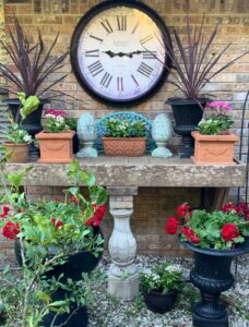 Garden bench with red geraniums and oversized clock