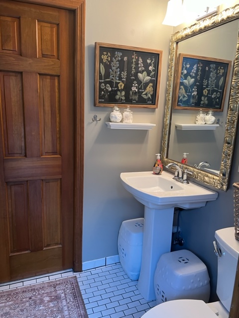 Bathroom with pedestal sink, 2 white ceramic garden stools and gilt framed mirror